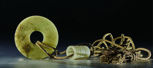 Ngoài miếng thủy tinh hình tròn, các nhà khảo cổ còn tìm thấy một miếng ngọc bích hình tròn tương tự trong ngôi mộ. (Ảnh: Sohu)